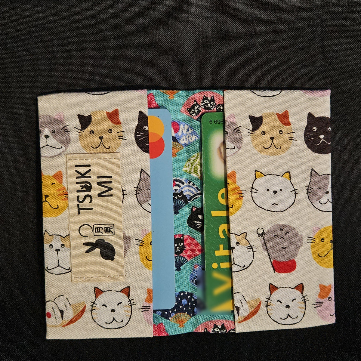Porte-cartes Tsukimi têtes de chats sur fond crème, ouvert avec deux cartes glissées dans les compartiments