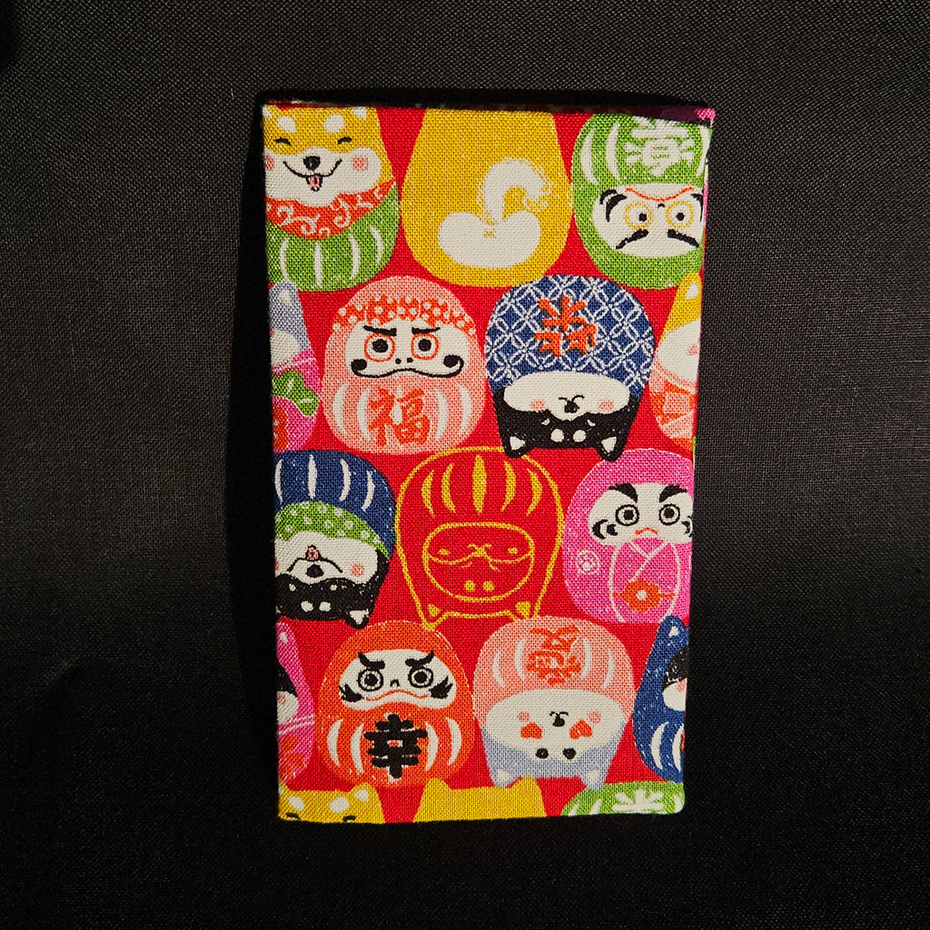 Porte-cartes Tsukimi fermé, en tissu japonais à darumas et shiba inu colorés sur fond rouge