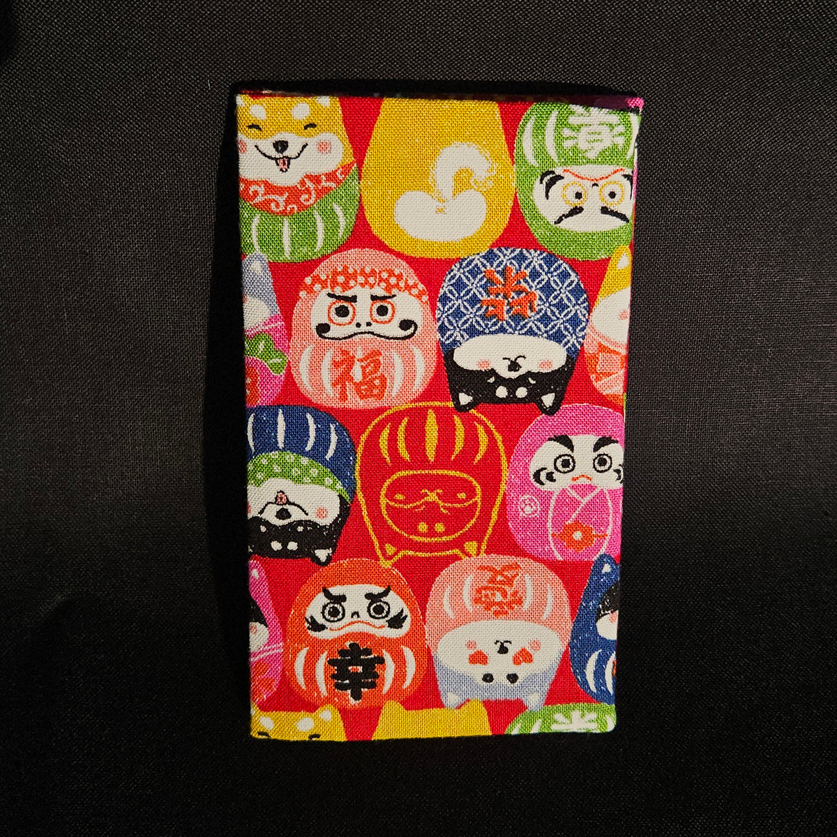 Porte-cartes Tsukimi fermé, en tissu japonais à darumas et shiba inu colorés sur fond rouge