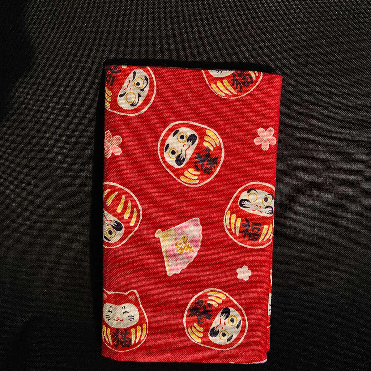 Porte-cartes Tsukimi fermé, en tissu japonais à grands darumas, shiba inu et chat porte-bonheur colorés sur fond rouge vif