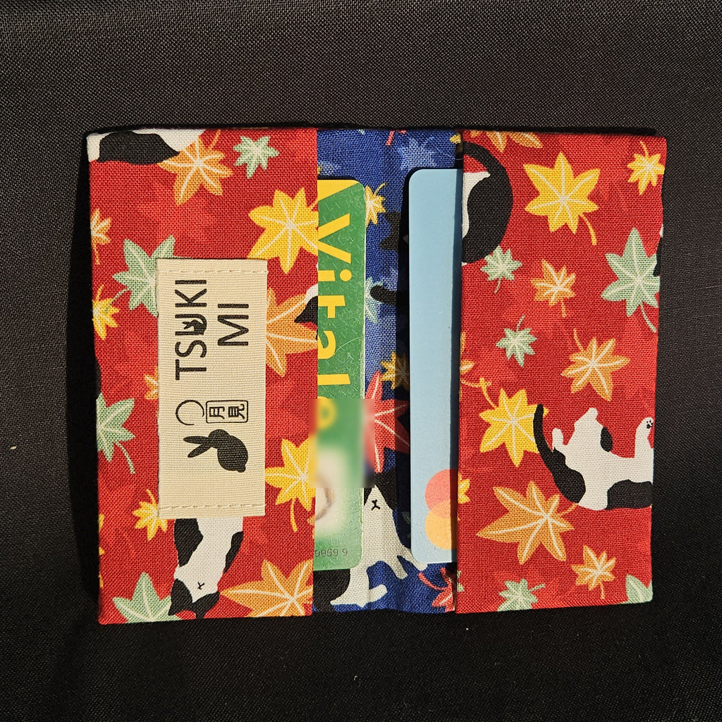 Porte-cartes Tsukimi érables et chats sur fond rouge, ouvert avec deux cartes glissées dans les compartiments
