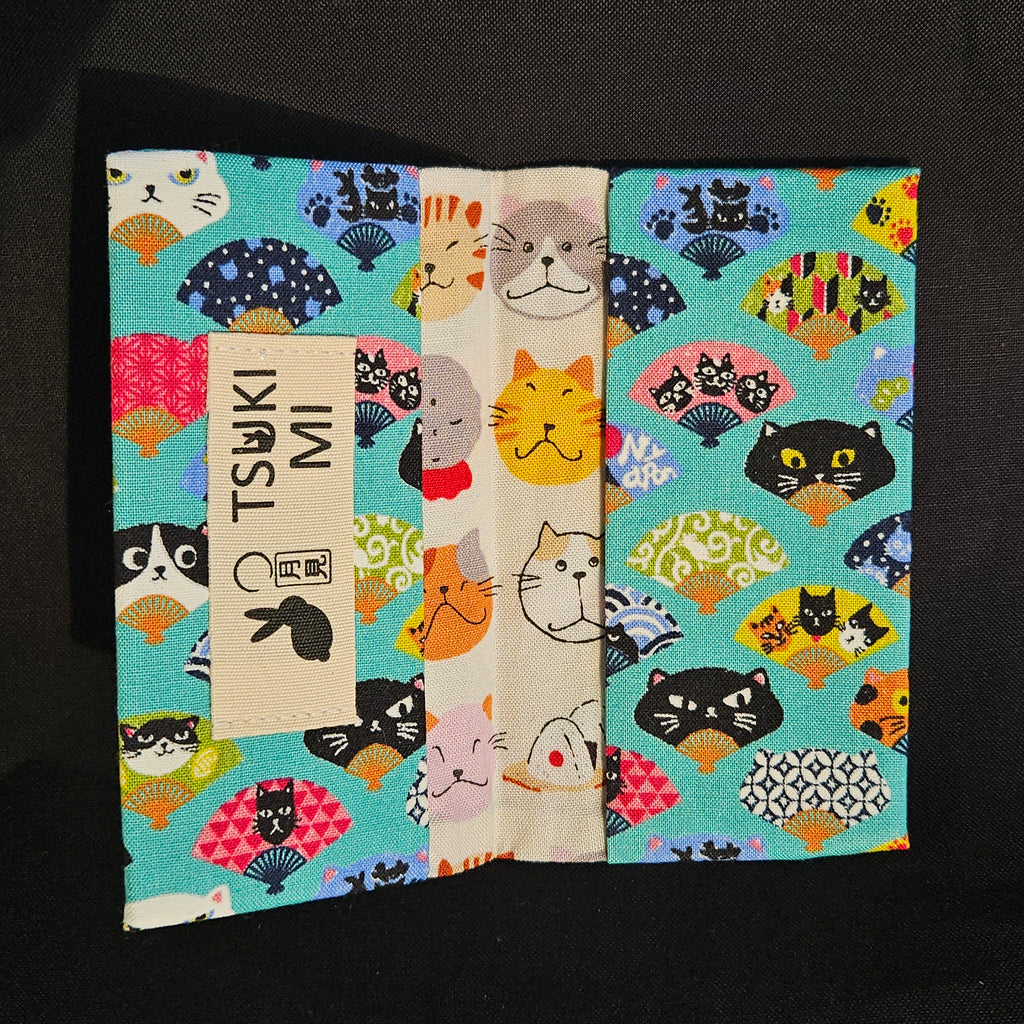 Porte-cartes Tsukimi ouvert : extérieur éventails et chats sur turquoise, intérieur crème à têtes de chats